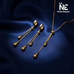 A studio shot of the full Tear Drop Jewelry Set arranged together on a deep blue satin fabric. The photo displays the gold-plated Y-shaped necklace and the coordinating dangling earrings with their tear drop charms.